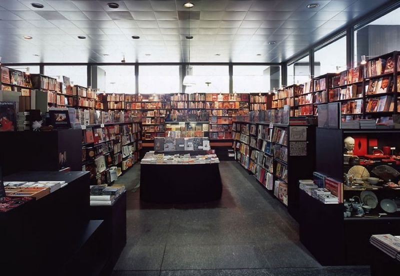 Buchhandlung mit dunklen Regalen und Büchertischen